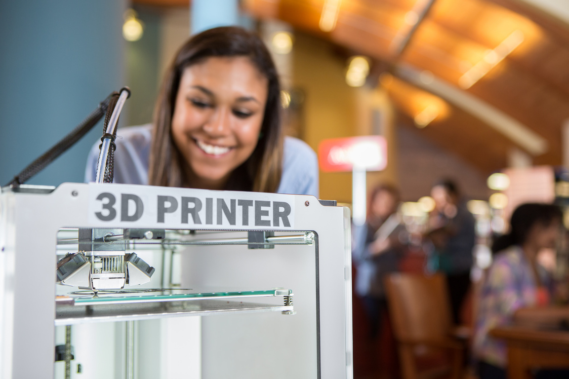 3D printer being used by college student in library makerspace