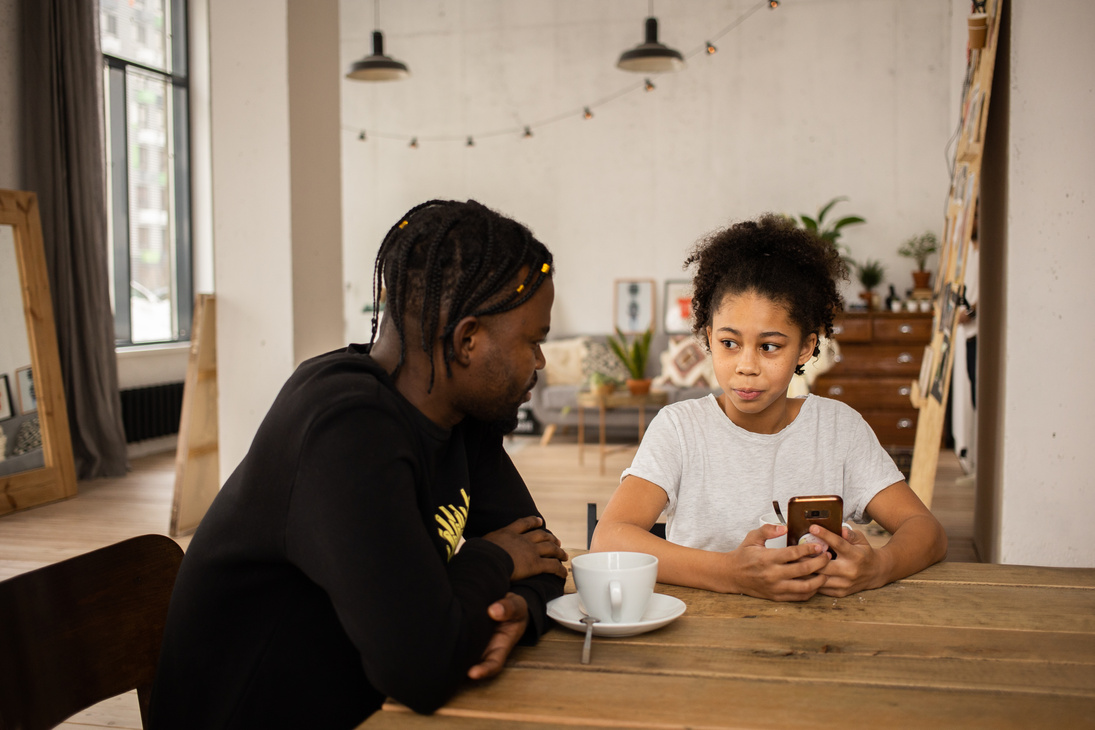 Black father talking to daughter using smartphone