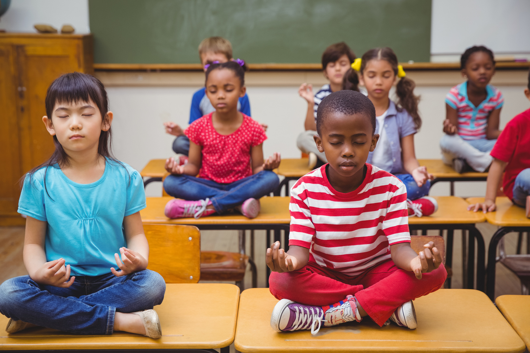 Pupils meditating in lotus position on desk